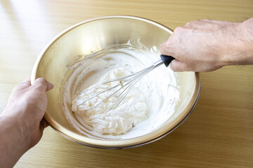 生クリームを泡立て器で泡立てる男のイメージ