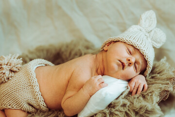 Cute baby in knitted panties and hat sleeping on fur plaid