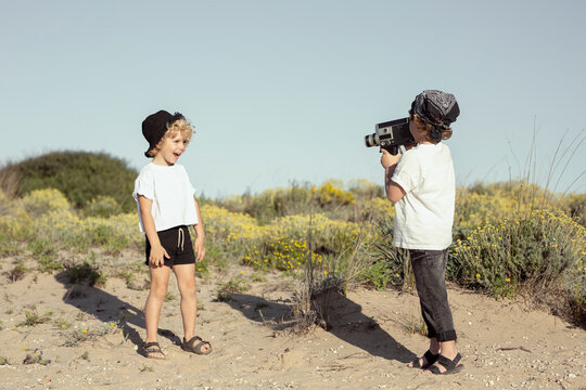 Happy little brothers recording video on beach