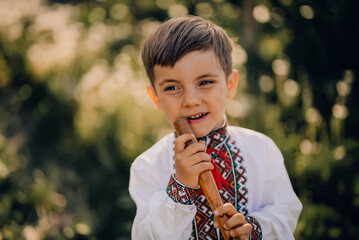 Portrait of little boy with woodwind wooden flute - ukrainian sopilka. Folk music concept. Musical...