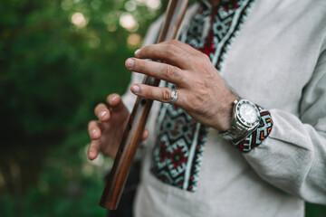 Hands of young man playing on woodwind wooden flute - ukrainian sopilka outdoors. Folk music...