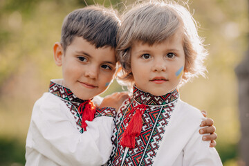 Smiling little ukrainian boys with blue yellow flag art on cheeks. Children together in traditional...