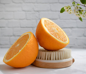 Massage brush, orange fruit, flower on a light background