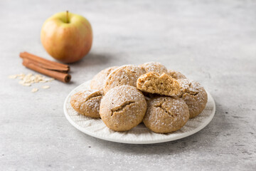 Steamed oatmeal cookies with apple and cinnamon sprinkled with powdered sugar on light gray textured background. healthy homemade food