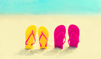 Summer vacation concept - colorful flip flops on the beach on sea background