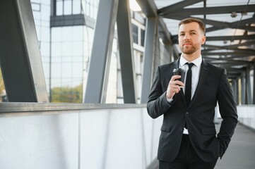 Bearded businessman in formal suit on break using mobile phone use smartphone. business man standing outside on modern urban city street background with coffee cup in downtown outdoors. copy space