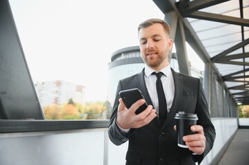 Close up serious businessman drinking take away coffee at street. Portrait of business man waiting with coffee to go outdoor. Office employee looking away at street. Male professional take break