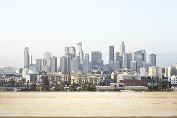 Blank wooden table top with beautiful Los Angeles skyline at daytime on background, mockup