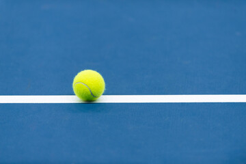 Yellow tennis ball with white line on blue court. Horizontal sport theme poster, greeting cards.