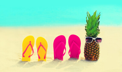 Summer vacation concept - pineapple with sunglasses and colorful flip flops on the beach on sea...