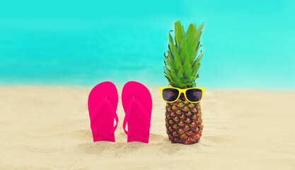 Summer vacation concept - pineapple with sunglasses and colorful flip flops on the beach on sea...