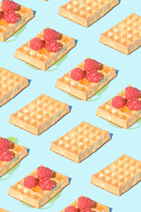 Fruit raspberry, honey and waffle arranged in a patern on a blue background. Visual aesthetic summer food concept.