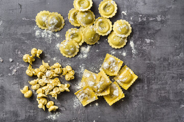 different types of fresh raw italian ravioli on the table with cooking ingredients. home kitchen