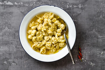 cappelletti in brodo. Italian dish for family holidays. on the table with parmesan