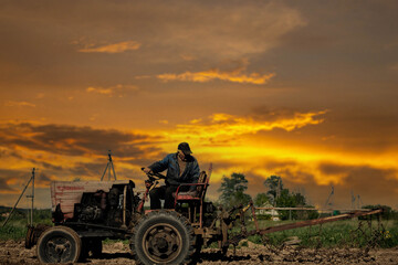 Obraz premium elderly man farmer rides a tractor across the field plowing the land. Village farming concept.