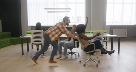 Man sits in chair recording cheerful colleagues on camera