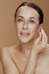 Portrait of modern woman with tweezers against beige background