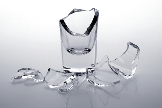 Shards of a broken glass stack on a white background.