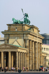 View of Brandenburg gate from north side with people walking on street in summer. Clear blue sky background.