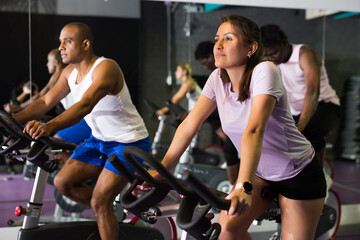 Fototapeta na wymiar Group of adult people training on exercise bikes in gym