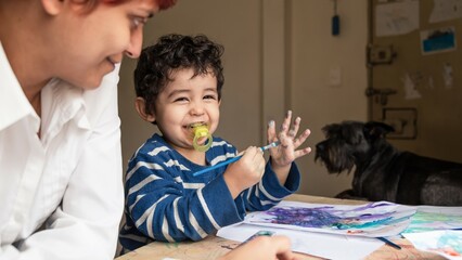 teacher teaching a child to paint with paints
