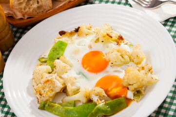 Plate of tasty fried eggs with cauliflower, green beans and condiment