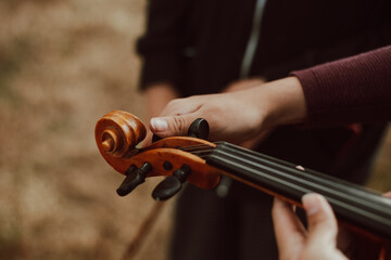 Manos de mujer afinando un  violín en una montaña al atardecer. Concepto de personas y música.
