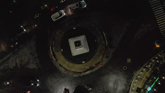 Top down view aerial footage of night traffic around monument intersection from drone flying and turning