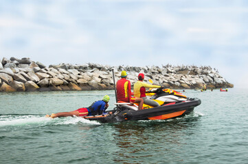 three rescuers navigate through the sea with the jet ski, to the rescue of a group of people