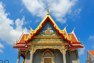Naklejka premium Front view of the Thai buddhist temple in Phuket, Thailand. Blue sky, copy space for text, wallpaper, golden, red, green, blue, horizontal image