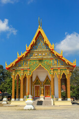 Fototapeta premium Entrance to the Thai buddhist temple in Phuket, Thailand. Blue sky, copy space for text, wallpaper, golden, red, green, blue, background