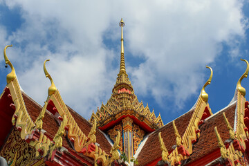 Fototapeta premium The roof of the Thai buddhist temple in Phuket, Thailand. Blue sky, copy space for text, wallpaper, golden, red, green