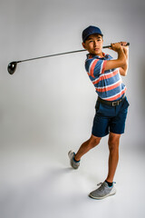 Young male golfer watching the ball after teeing off
