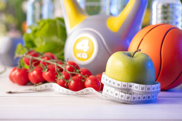 Fitness concept. Healthy nutrition: fruits and vegetables. Equipment for fitness exercises: weighing machine and dumbells on  wooden wwhite table.