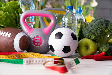 Naklejka premium Fitness concept. Healthy nutrition: fruits and vegetables. Equipment for fitness exercises: weighing machine and dumbells on wooden wwhite table.