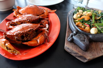 Delicious looking cooked crab with spicy sauce served on red plate. Indonesian famous seafood dish. Kepiting Dandito from Balikpapan, Kalimantan.