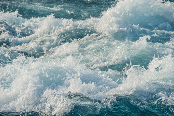 Bubbling ocean water at high tide. Turquoise sea waves foam, break into splashes.