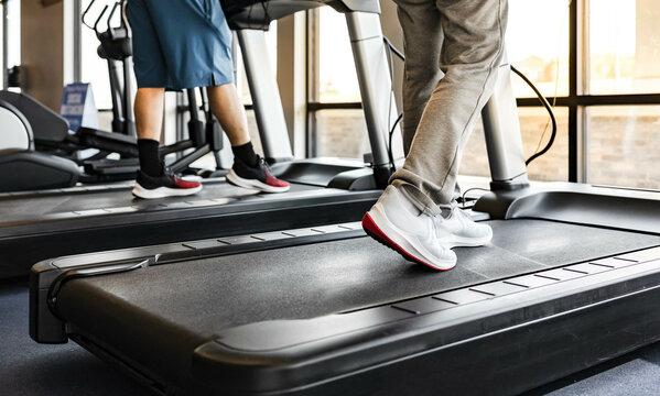 Group of people walking on a treadmill. Crop image of unrecognizable athlete cool down on running track machine. Cardio training for healthy physical, weight loss in the gym. Indoor workout lifestyle.