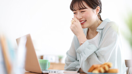 パソコンを見ながら笑う若い女性