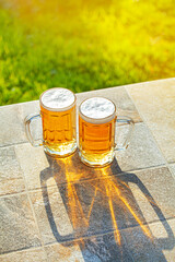 Cerveja 2 copos chopp em dobro em base de pedra com fundo de natureza verde