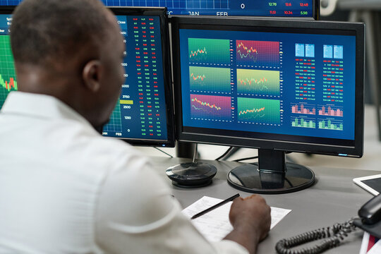African American man working on stock trading watching charts and graphs of currency, selective focus shot