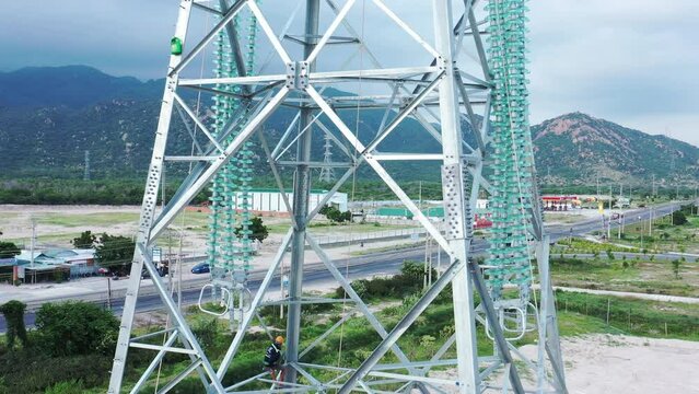 Aerial drone footage of high-voltage power towers with prefabricated glass insulators to distribute electricity in an industrial park - Development and urbanization concept