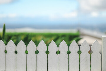Close up image of white picket fence with beautiful beach scenery out of focus in background...