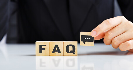 Businessman is placing a wooden block with a chat icon next to a wooden block with the word FAQ (...