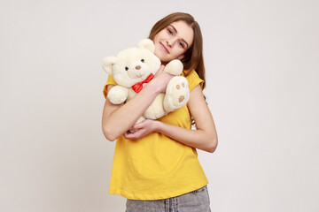 Portrait of happy pleasant looking teenager girl wearing yellow T-shirt hugging romantic present...