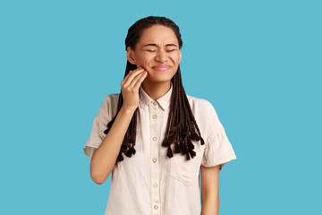 Displeased woman suffers from toothache, touches cheek, needs to see dentist, has health problems,...