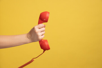 Profile side view closeup of woman hand holding and showing red call telephone handset receiver....