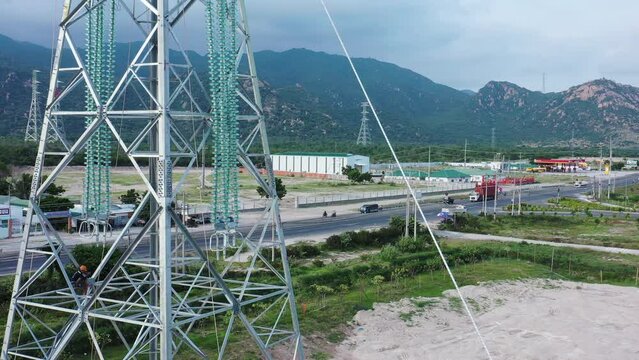 Aerial drone footage of high-voltage power towers with prefabricated glass insulators to distribute electricity in an industrial park - Development and urbanization concept