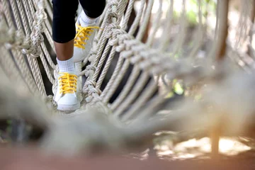 Foto op Canvas Little child girl play walking on rope bridge on adventure park, close up © chomplearn_2001
