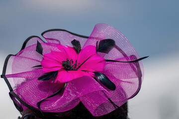 An attendee at a horse race, wearing a fancy hat.